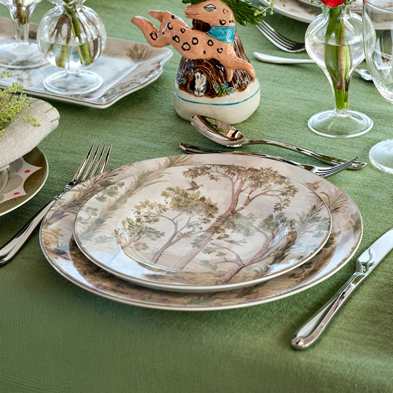 Spode Kit Kemp dinnerware featuring delicate tree and woodland motifs in soft earth tones, styled with whimsical rabbit figurine and elegant table setting